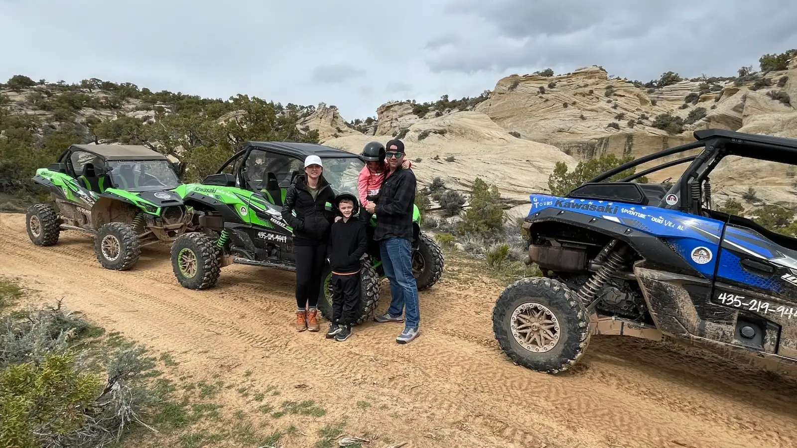 A family beside the branded Kawasaki KRX 1000 fleet on a beginner-friendly desert trail near Vernal, Utah